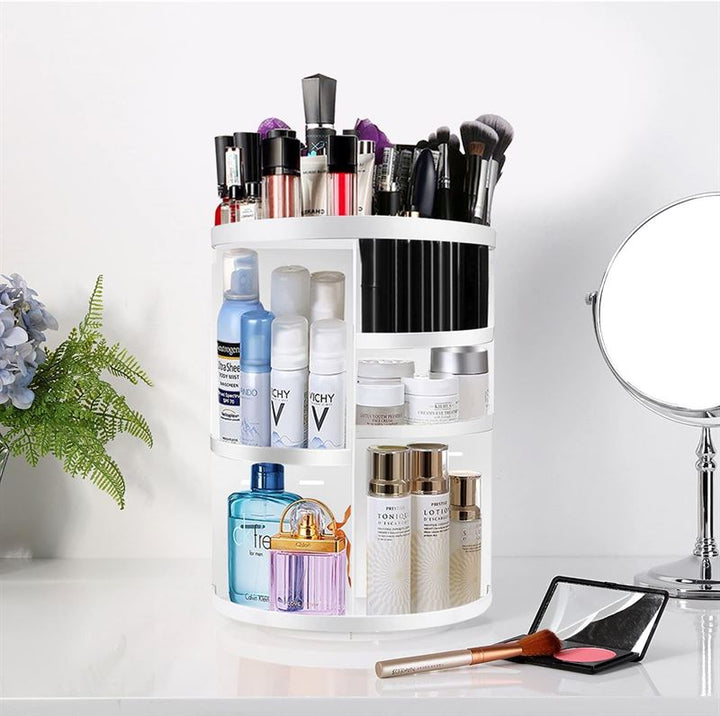 The UNIQ 360° Rotating Makeup Organizer in white neatly stores lipsticks, brushes, skincare bottles, and perfumes on your vanity, beside a mirror and compact, offering stylish cosmetic storage from UNIQ.