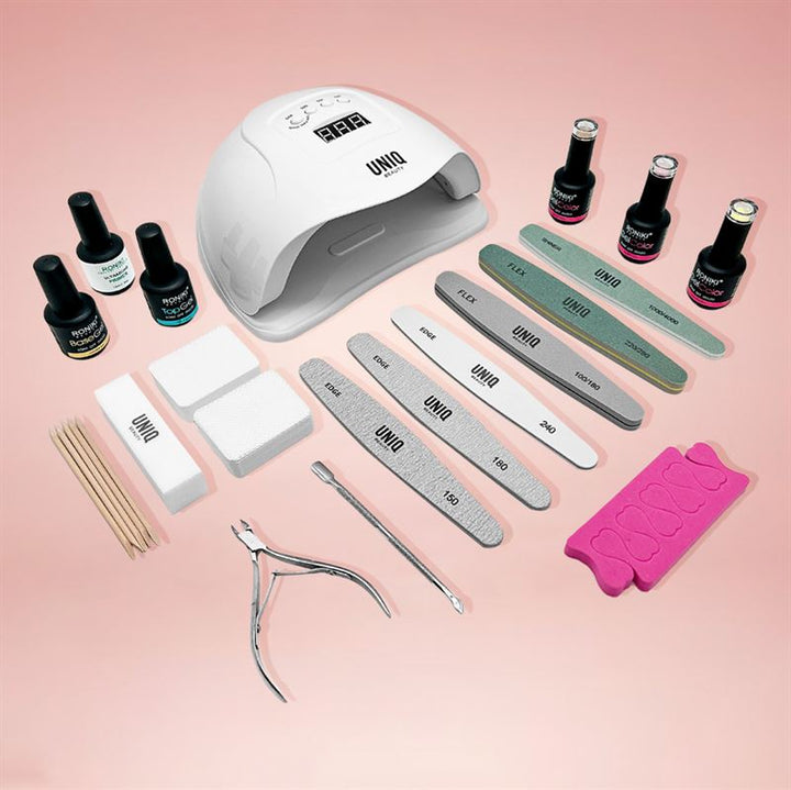 The UNIQ Premium Gel Polish Starter Kit, by UNIQ, features a white UV/LED lamp, nail files, buffers, wooden sticks, clippers, toe separators, and several gel polishes plus base/top coats—everything you need for perfect gel nails at home.